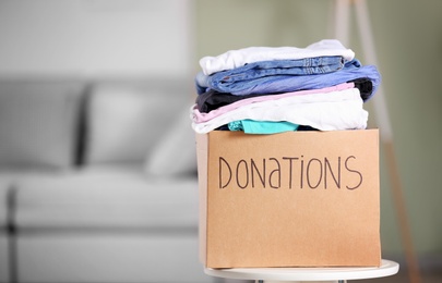 Donation box with clothes on table indoors