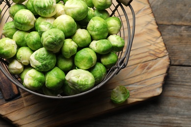 Photo of Metal basket with fresh Brussels sprouts on wooden background, top view