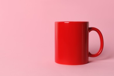 Photo of One red ceramic mug on pink background. Space for text