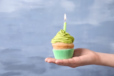 Photo of Woman holding birthday cupcake on blurred background