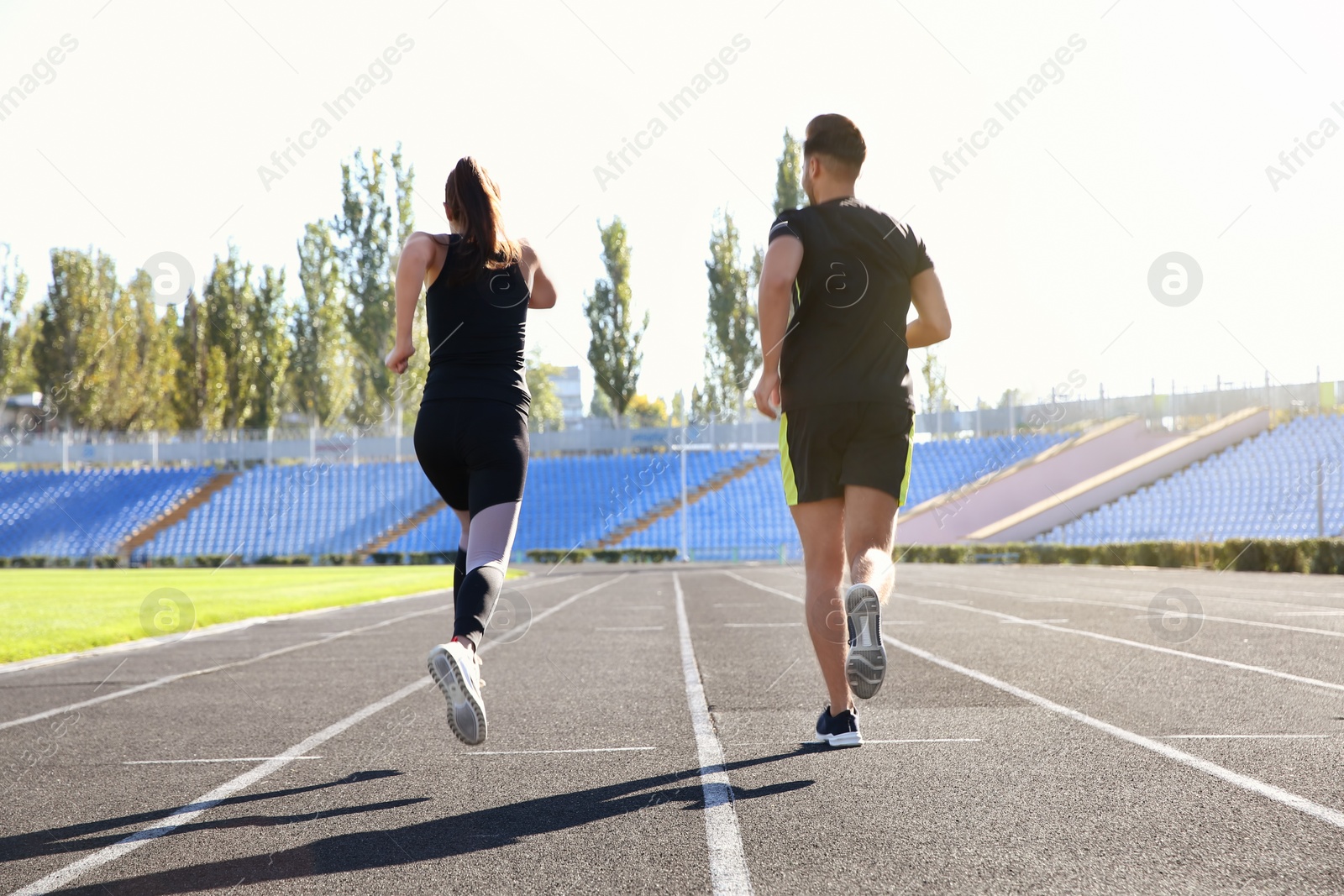 Photo of Sporty couple running at stadium on sunny morning