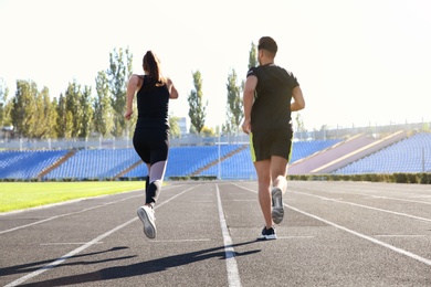 Sporty couple running at stadium on sunny morning