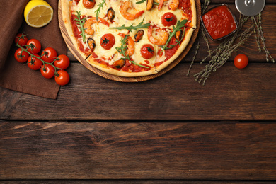 Photo of Delicious seafood pizza on wooden table, flat lay. Space for text