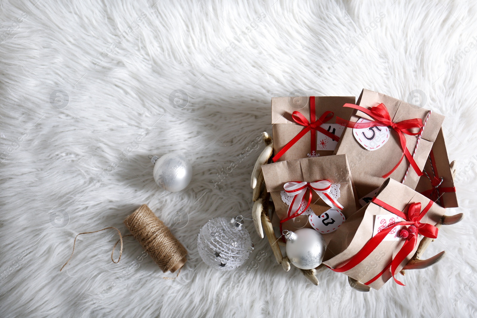 Photo of Christmas gifts and festive decor on white fluffy rug, flat lay with space for text. Creating Advent calendar