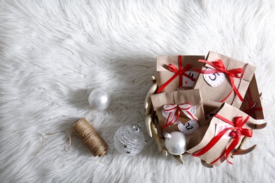 Photo of Christmas gifts and festive decor on white fluffy rug, flat lay with space for text. Creating Advent calendar