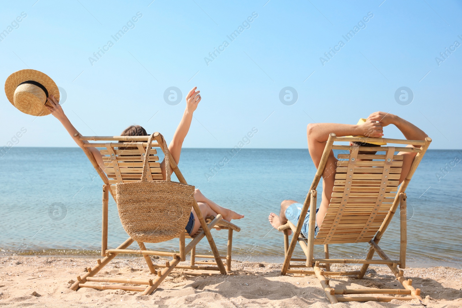 Photo of Young couple relaxing in deck chairs on beach