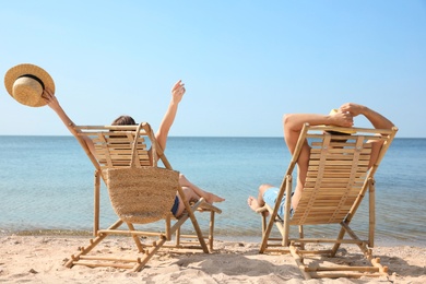 Photo of Young couple relaxing in deck chairs on beach