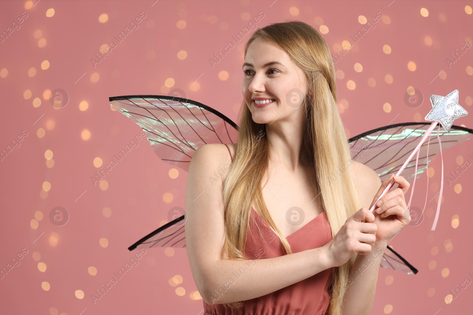 Photo of Beautiful girl in fairy costume with wings and magic wand on pink background