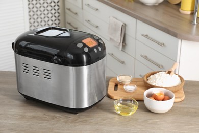 Breadmaker and products on wooden table in kitchen