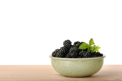 Photo of Bowl with fresh ripe blackberries on wooden table against white background, space for text