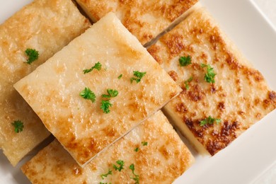 Photo of Delicious turnip cake with parsley on plate, top view