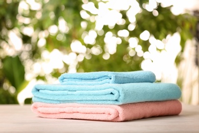 Photo of Pile of fresh towels on table against blurred background, space for text