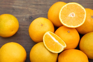 Many whole and cut oranges on wooden table, closeup