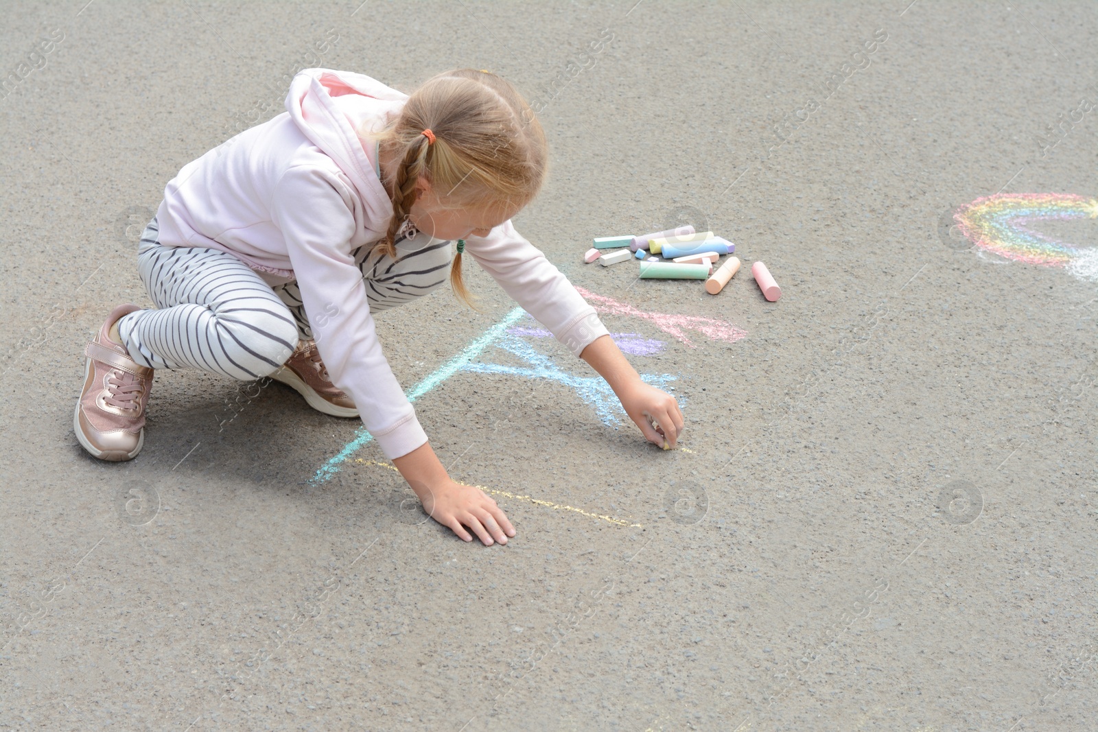 Photo of Little child drawing happy family with chalk on asphalt