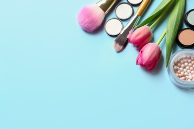 Makeup products and flowers on color background, flat lay with space for text
