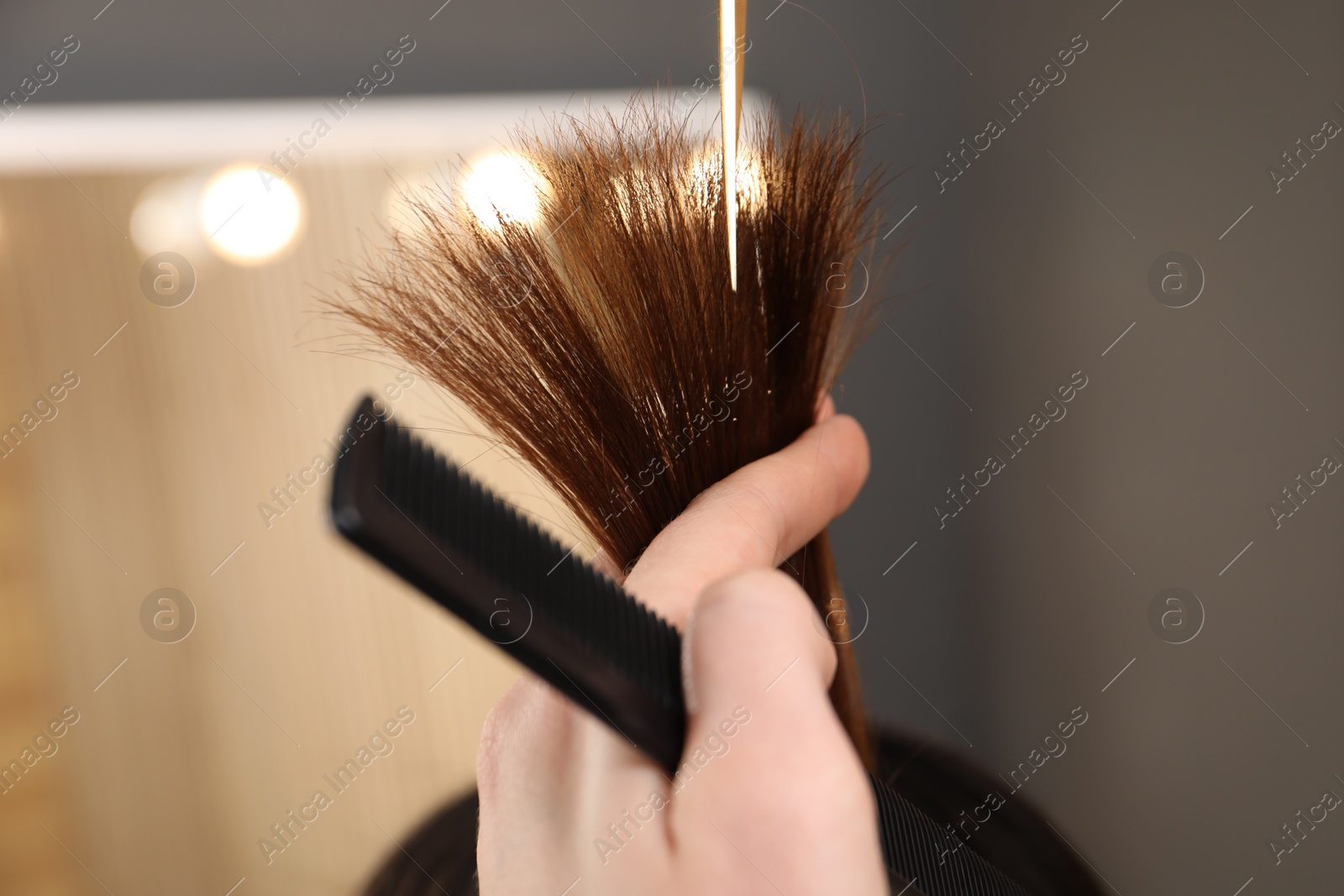 Photo of Hairdresser cutting client's hair with scissors in salon, closeup