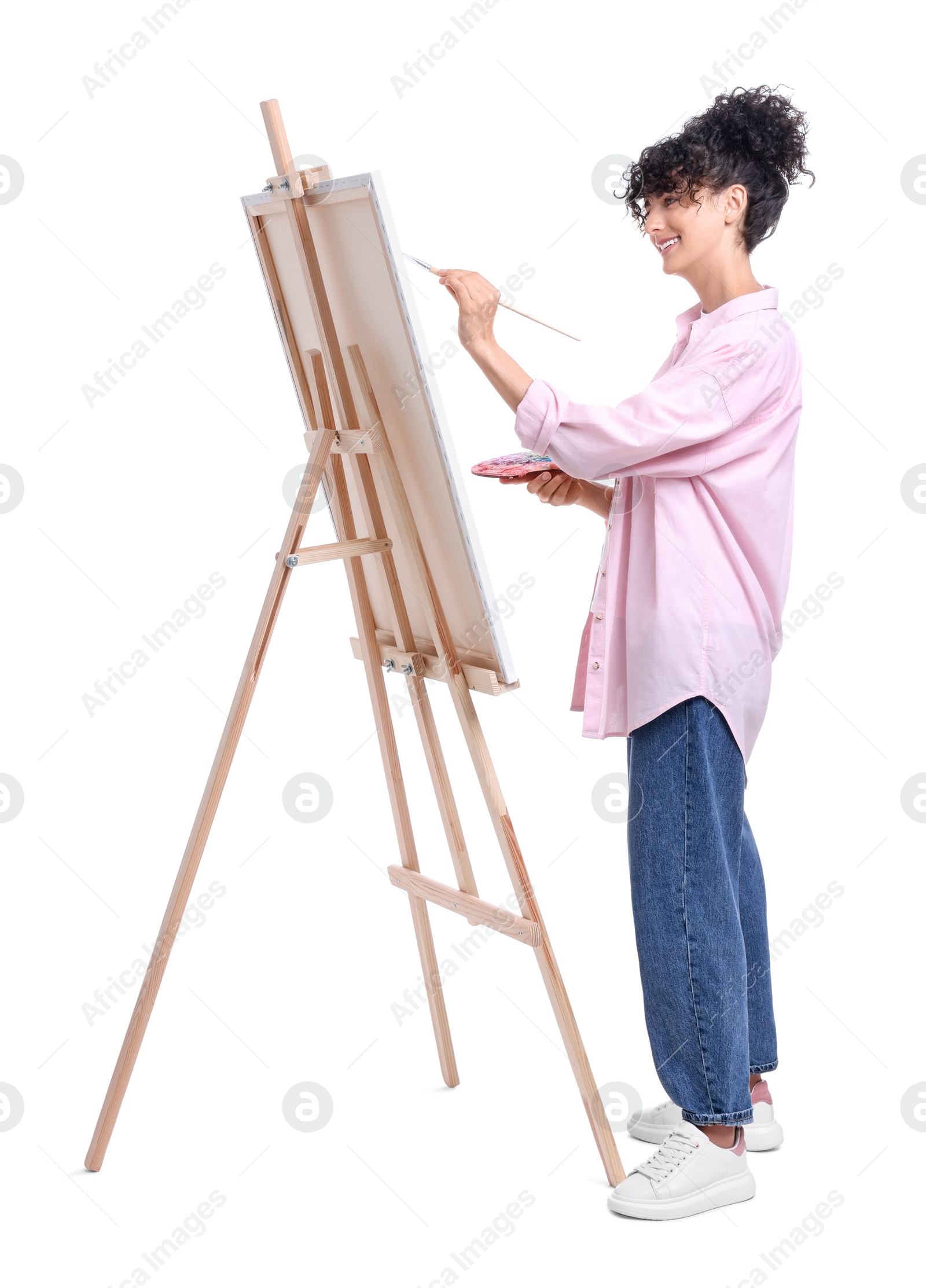 Photo of Young woman painting on easel with canvas against white background