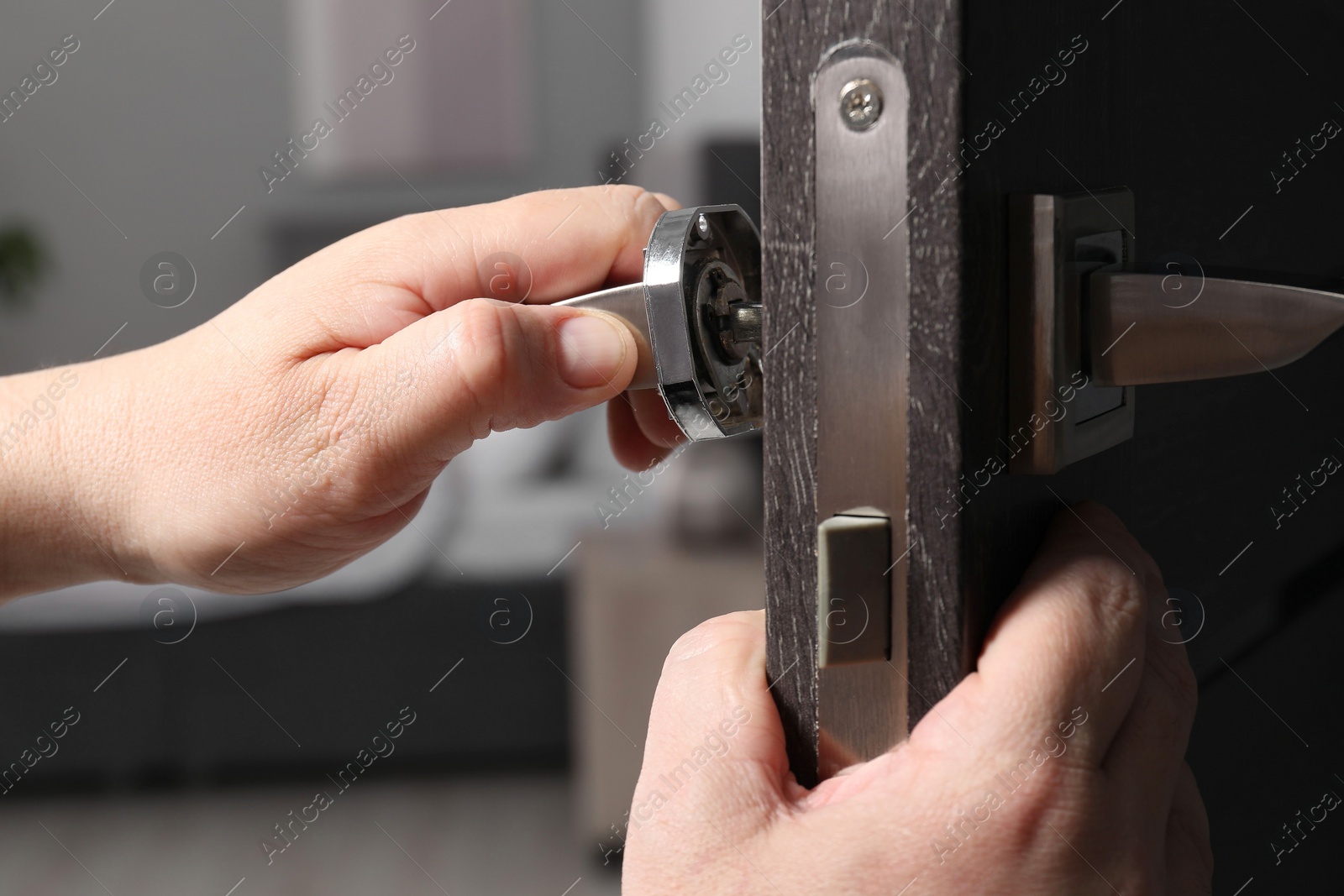 Photo of Handyman repairing door handle indoors, closeup view