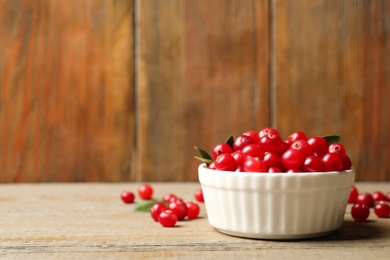 Tasty ripe cranberries on wooden table, closeup. Space for text