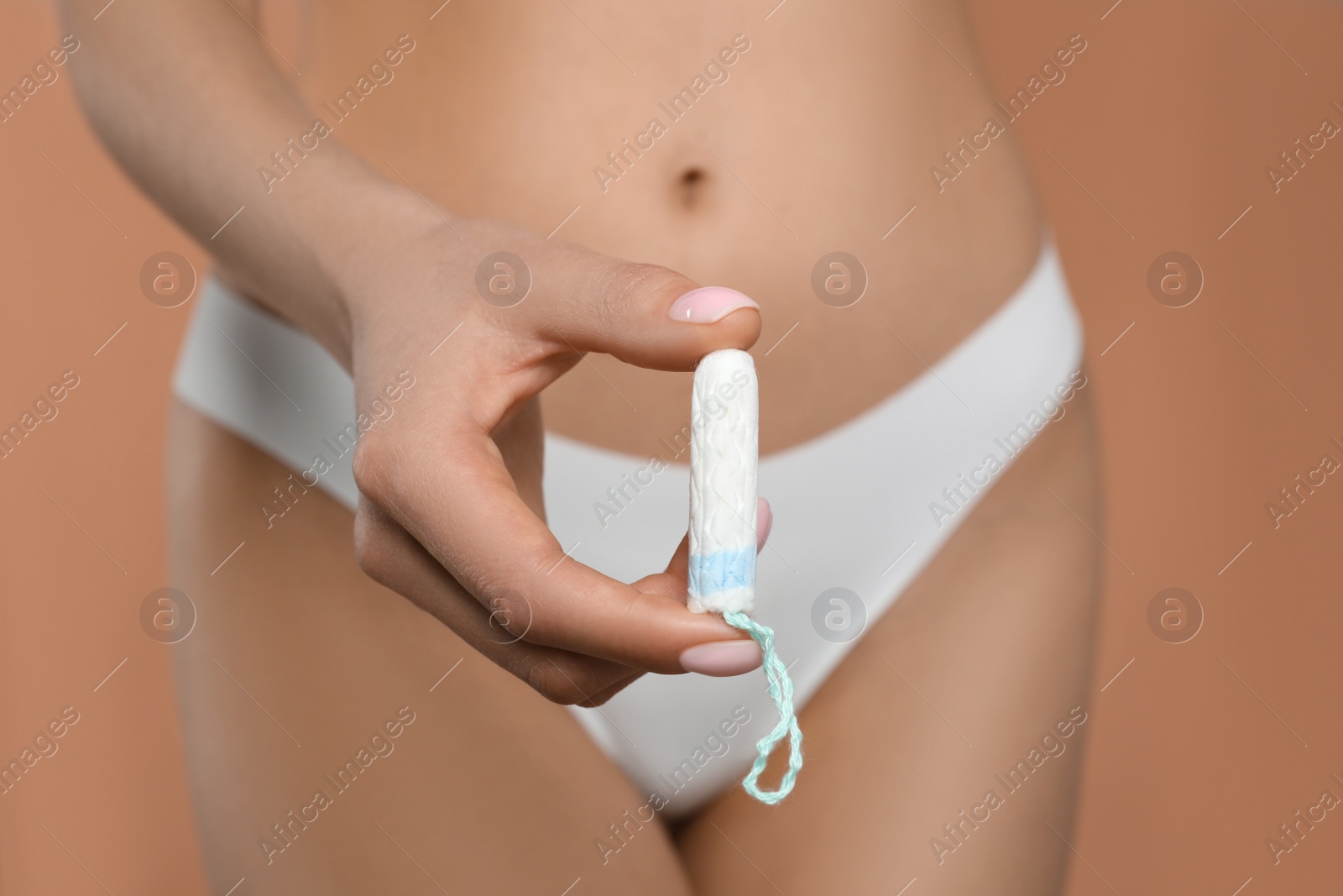 Photo of Woman in white panties with tampon on peach background, closeup