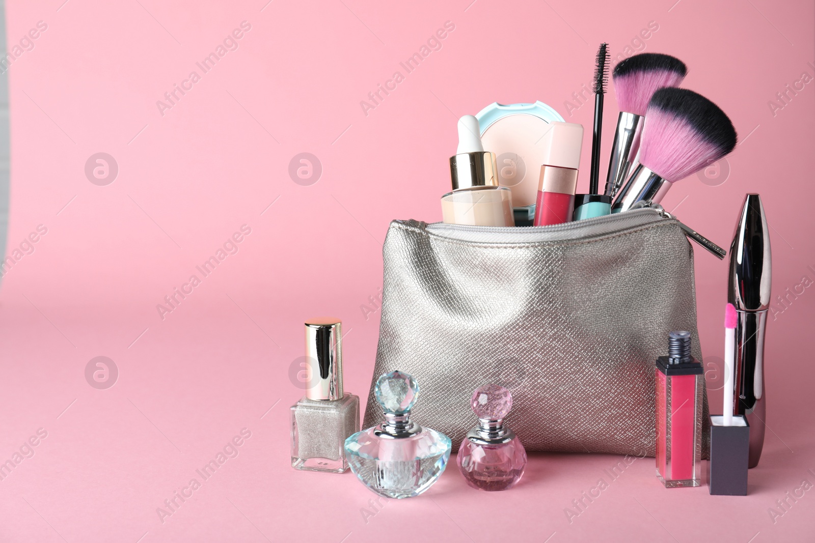 Photo of Cosmetic bag and makeup products with accessories on pink background. Space for text