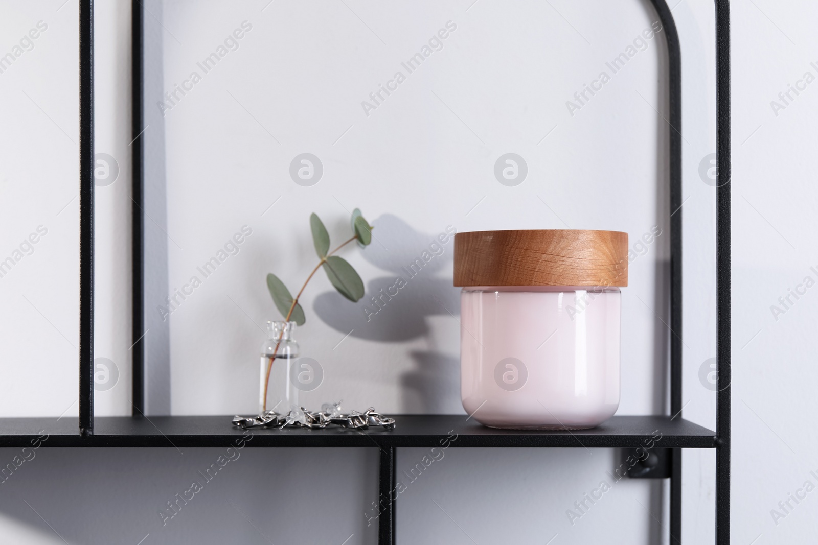 Photo of Jar of hand cream, jewelry and eucalyptus branch on shelf