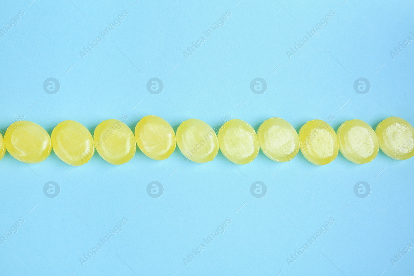 Photo of Many delicious lemon drops on light blue background, flat lay