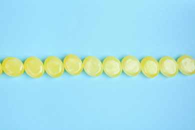 Many delicious lemon drops on light blue background, flat lay