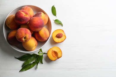 Fresh sweet peaches on white wooden table, flat lay. Space for text