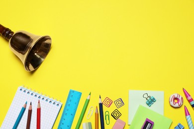 Photo of Different stationery and school bell on yellow background, flat lay. Space for text