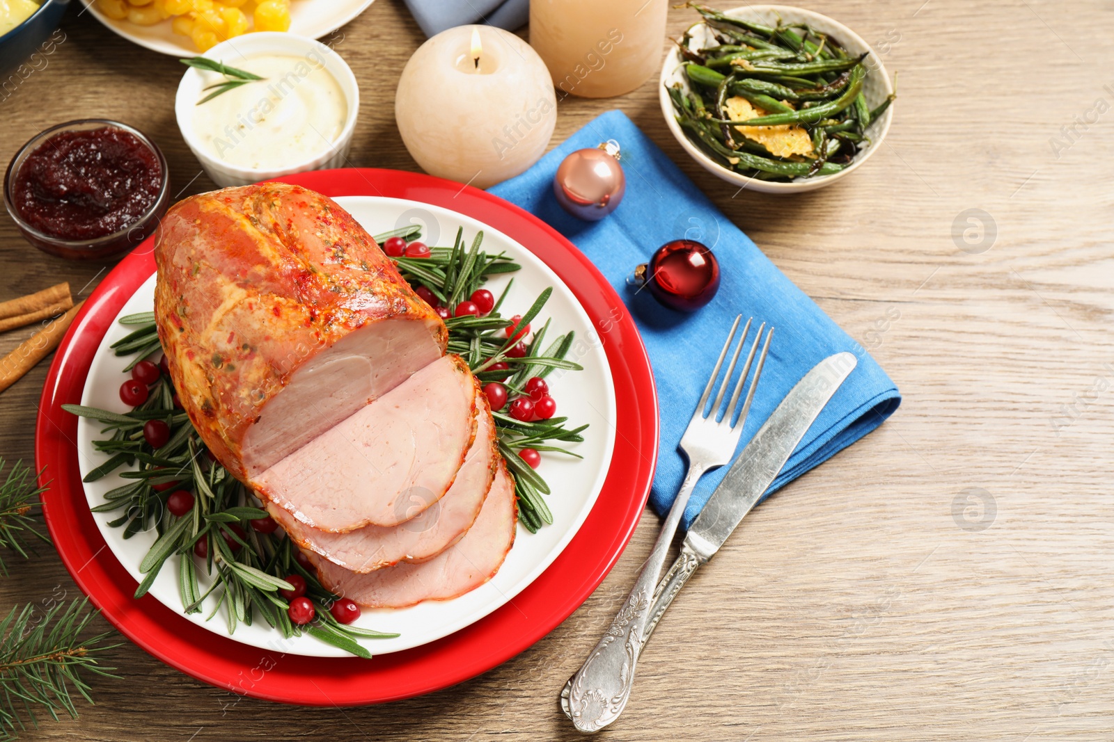 Photo of Delicious Christmas ham served with garnish on wooden table, above view