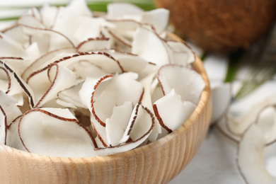 Tasty coconut chips in wooden bowl, closeup