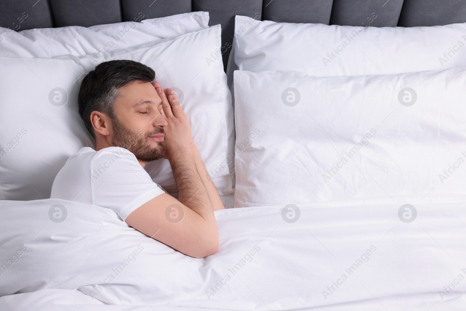 Photo of Handsome man sleeping in soft white bed