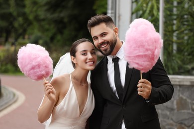 Happy newlywed couple with cotton candies outdoors