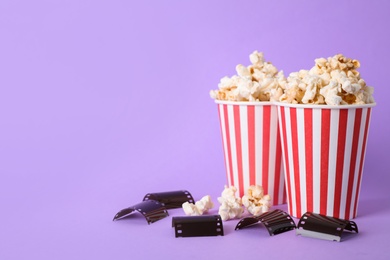 Photo of Delicious popcorn and tape on lilac background. Space for text