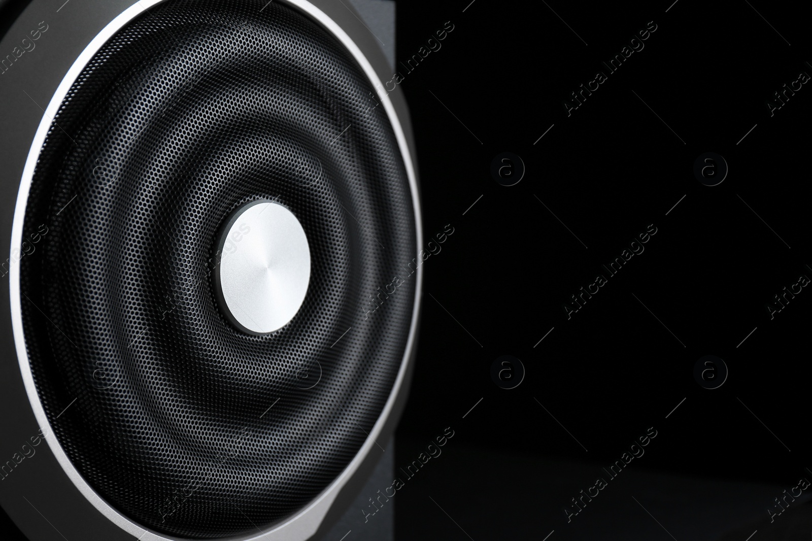 Photo of Closeup view of modern subwoofer on black background, space for text. Powerful audio speaker