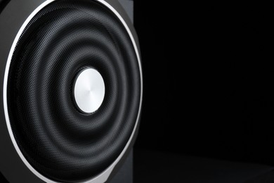 Closeup view of modern subwoofer on black background, space for text. Powerful audio speaker