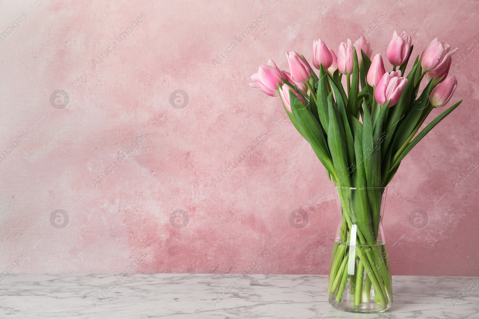 Photo of Beautiful pink spring tulips on marble table. Space for text