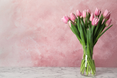 Photo of Beautiful pink spring tulips on marble table. Space for text