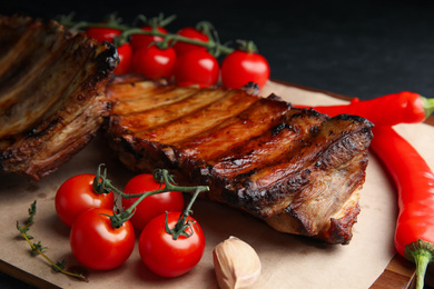 Photo of Tasty grilled ribs with tomatoes and peppers on table, closeup