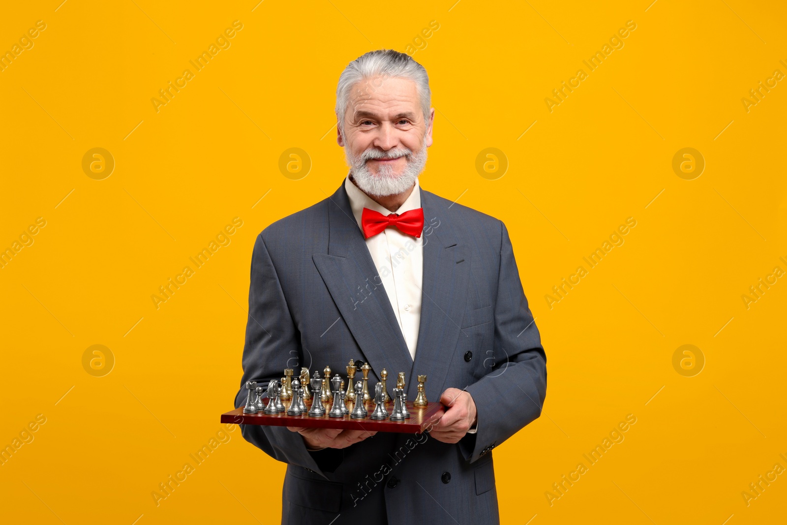 Photo of Man with chessboard and game pieces on orange background