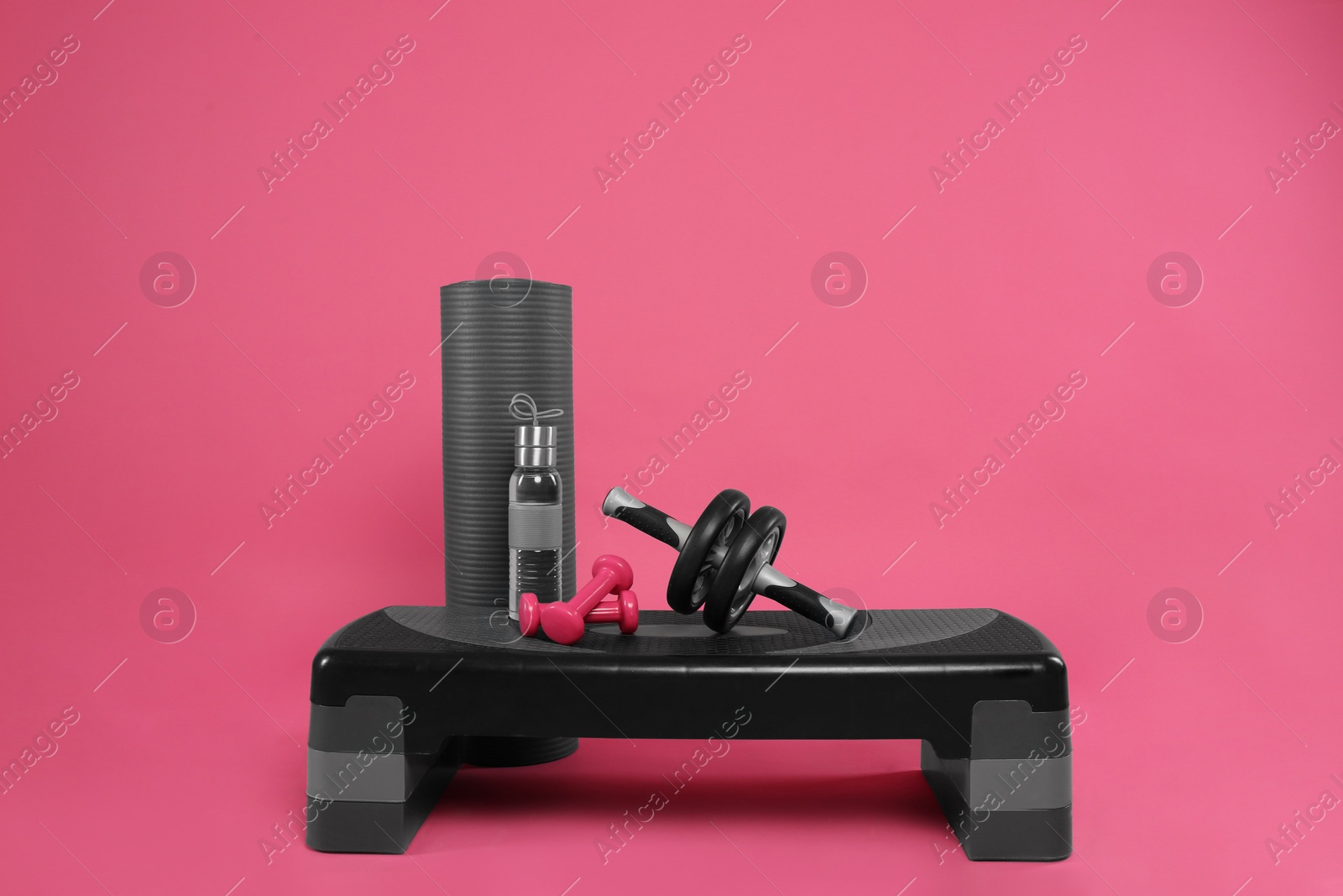 Photo of Step platform with bottle of water and other sports equipment on pink background