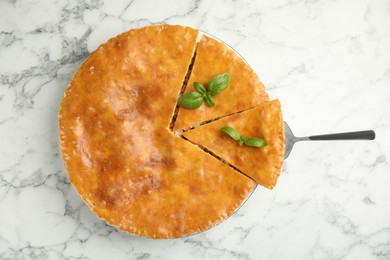 Photo of Delicious pie with meat and basil on white marble table, top view