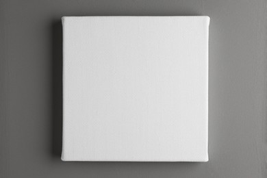 Blank canvas hanging on grey wall, space for text