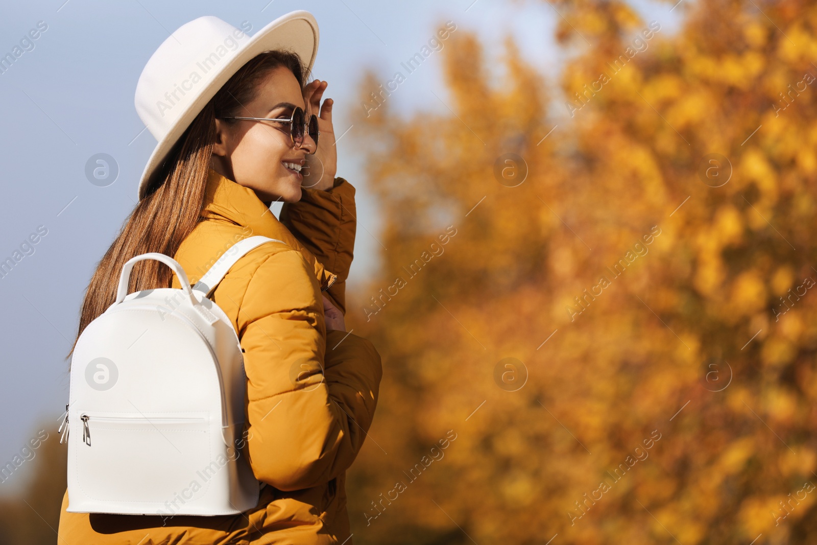 Photo of Young woman with stylish backpack on autumn day, space for text