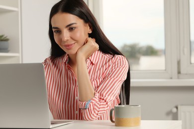 Photo of Young woman working with laptop at workplace in office
