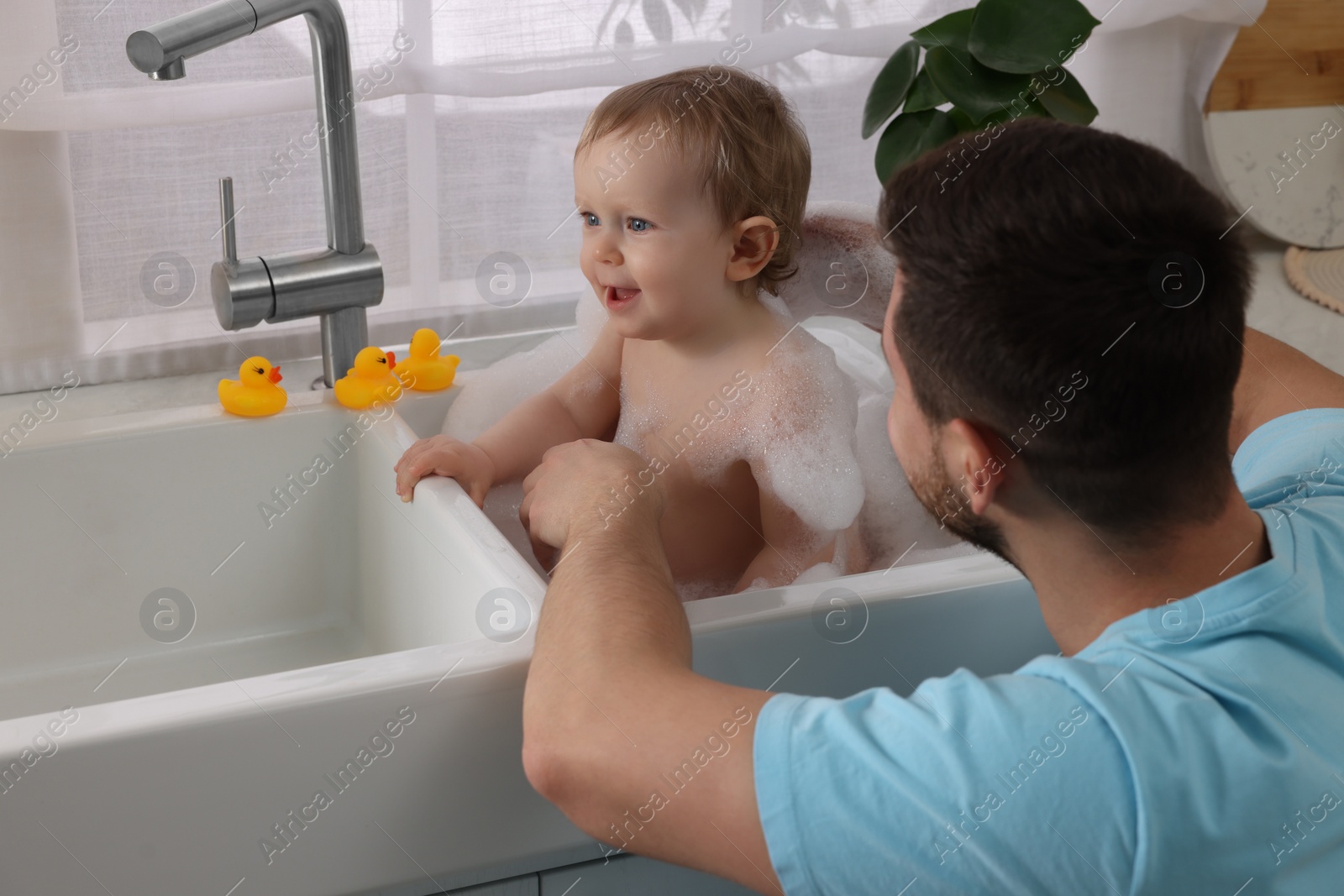 Photo of Father washing his little baby in sink at home