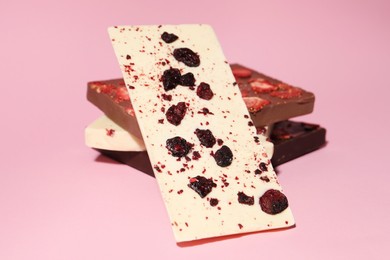 Photo of Different chocolate bars with freeze dried fruits on pink background