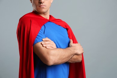 Photo of Man wearing superhero cape on grey background, closeup. Space for text