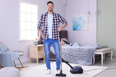 Photo of Mature man hoovering carpet with vacuum cleaner at home